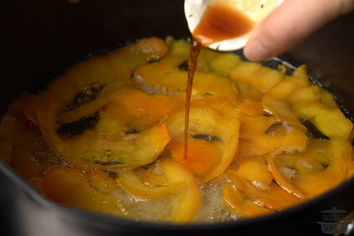 Vanilla being added to the sugar syrup and oranges