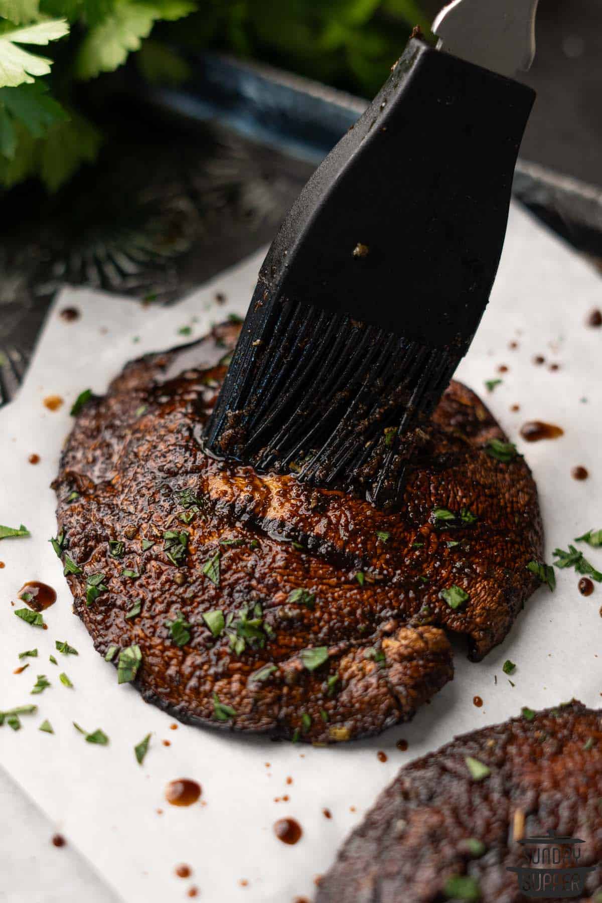 more marinade being brushed on a grilled portobello mushroom