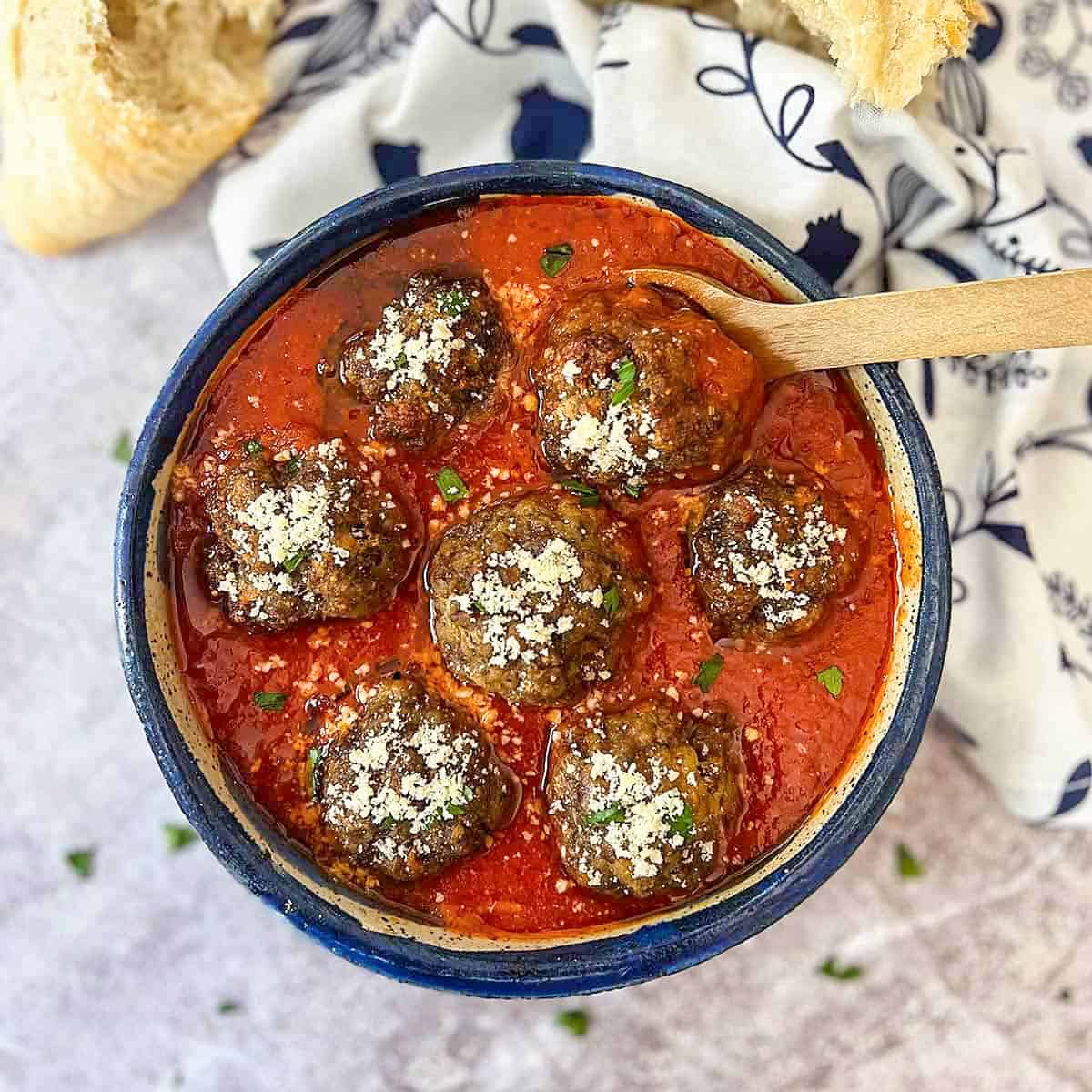 closeup of italian meatballs in a bowl with tomato sauce and a spoon