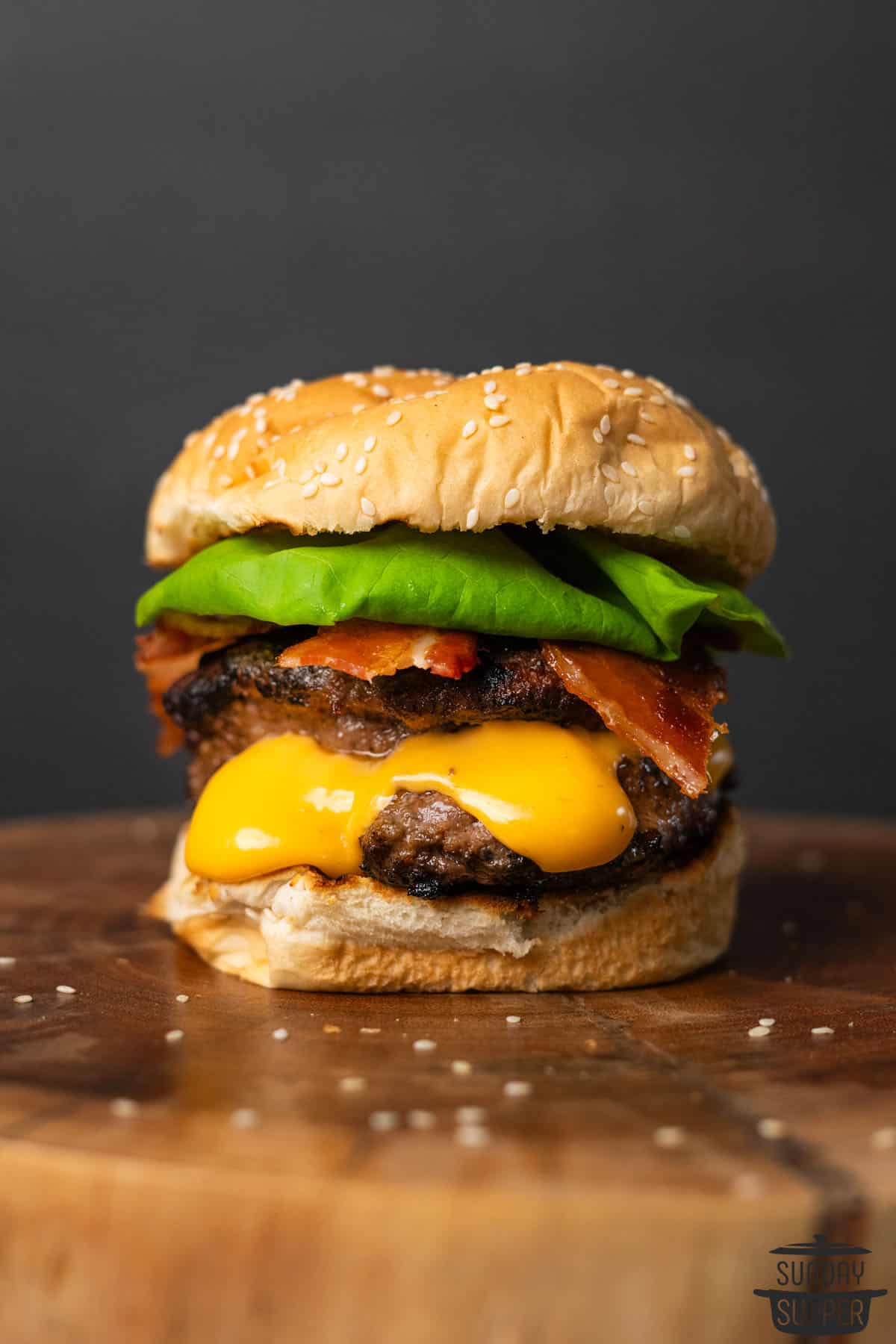 a loaded juicy lucy burger on a cutting board with toppings