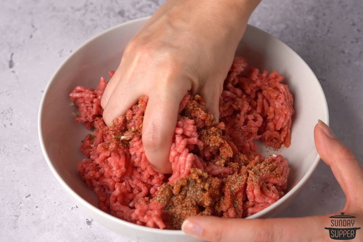 mixing the seasonings into the hamburger