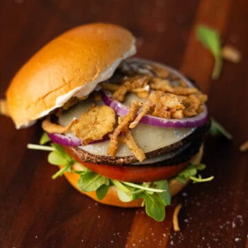 a completed portobello mushroom burger with cheese and fried onion toppings