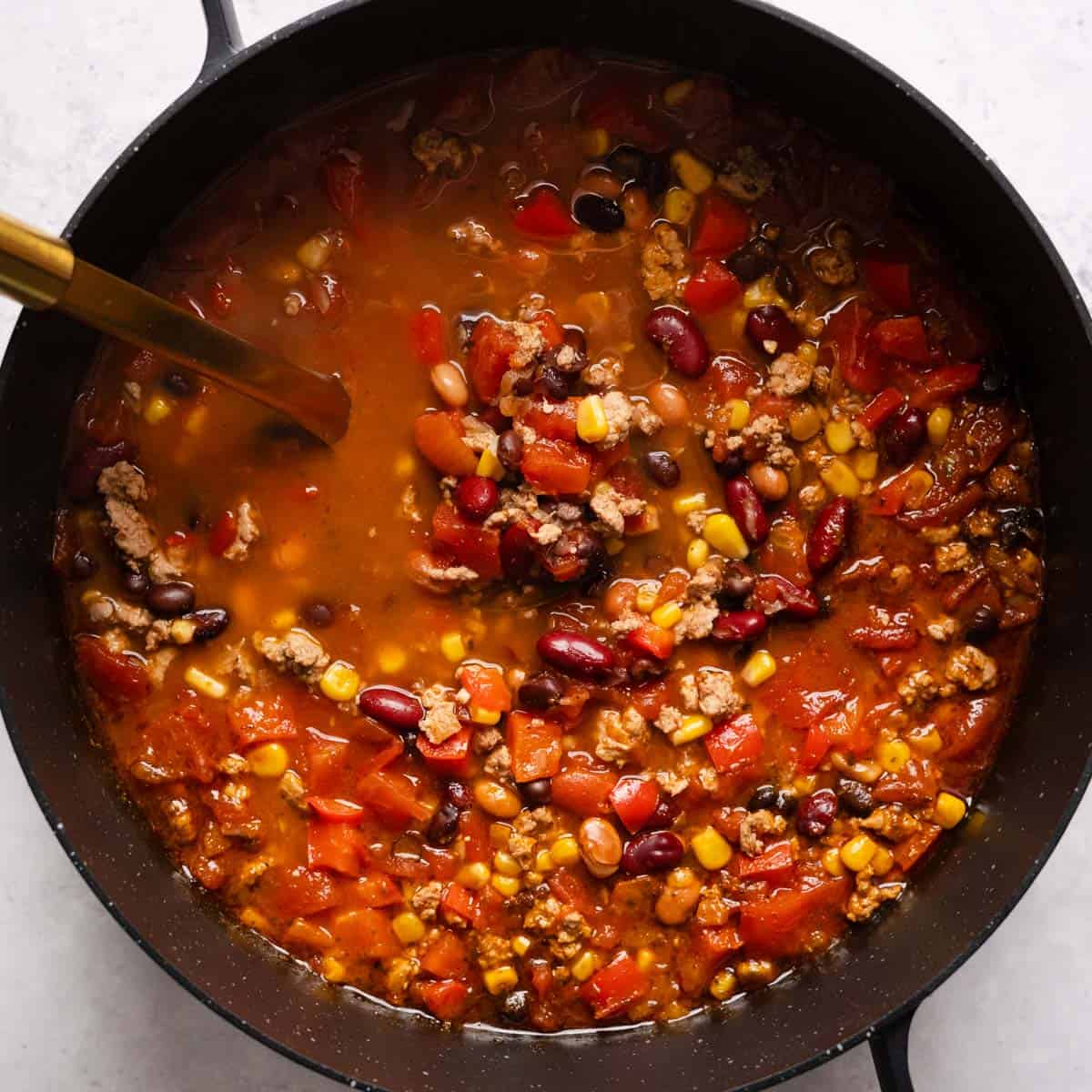 a pot of turkey chili with a serving spoon