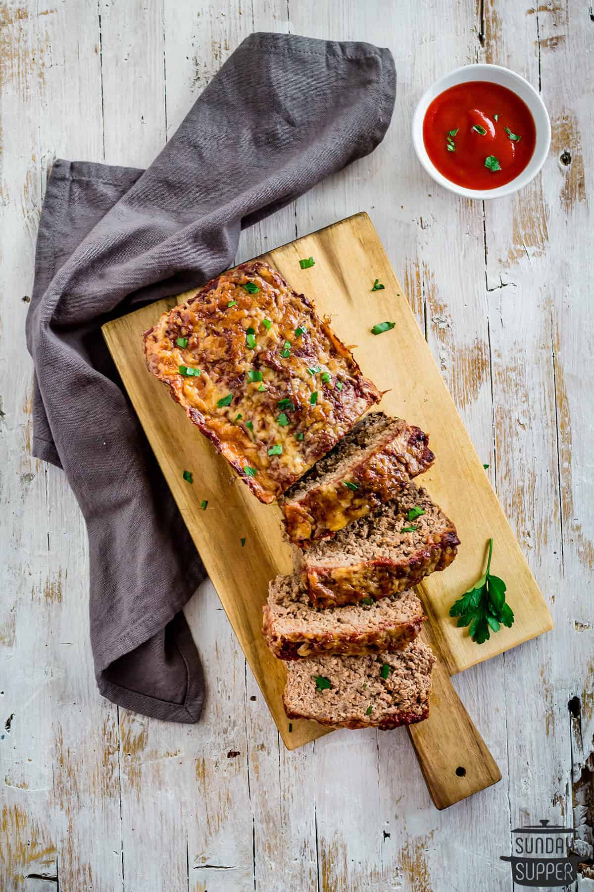 a sliced keto meatloaf on a cutting board with ketchup to the side