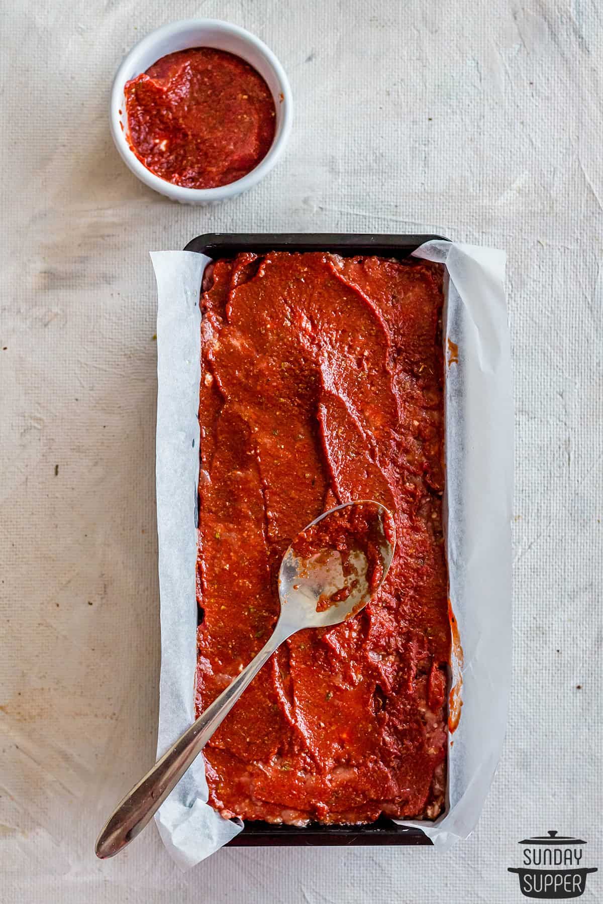 spreading meatloaf glaze over meatloaf before baking