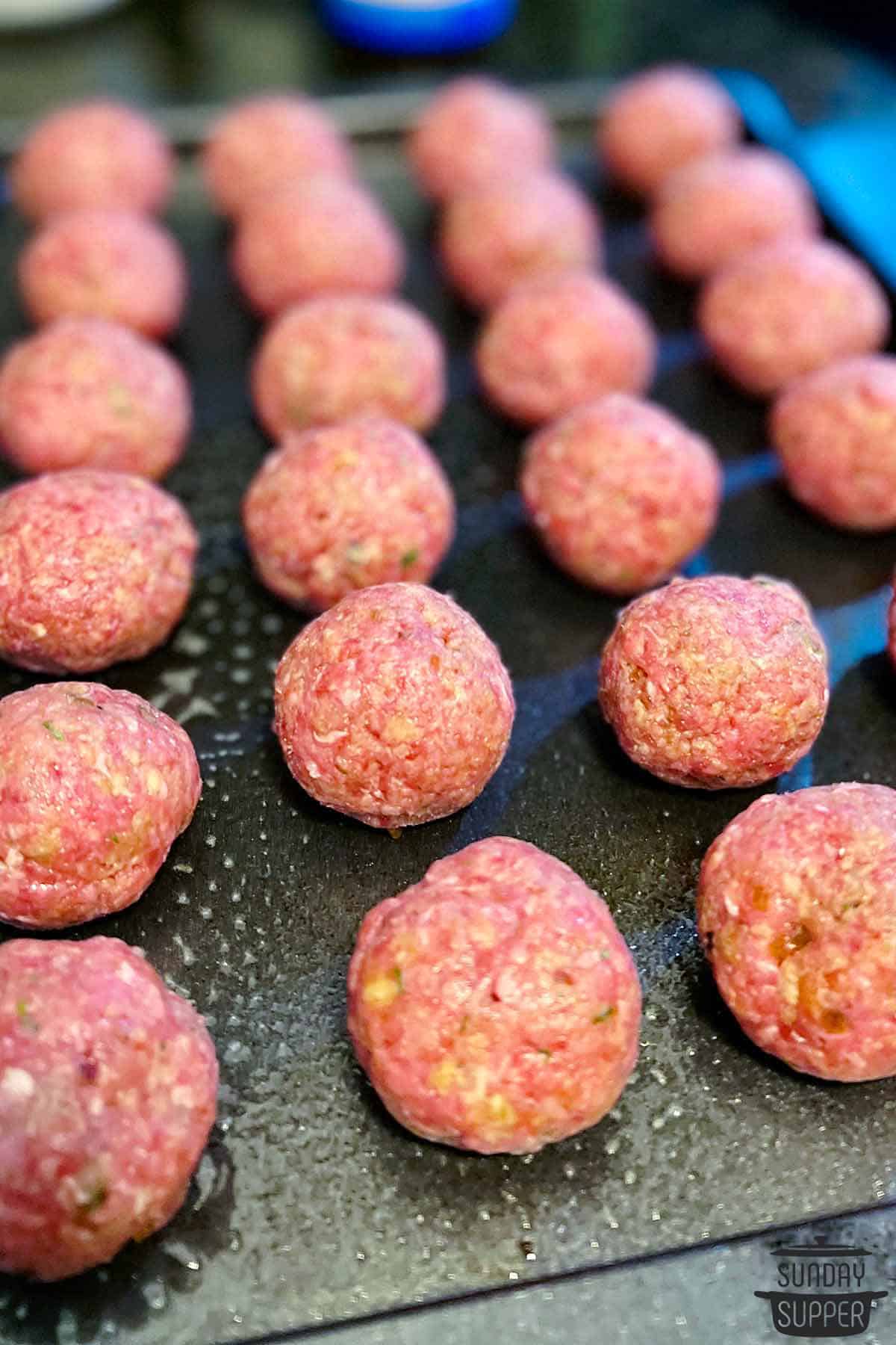 uncooked meatballs on a baking tray