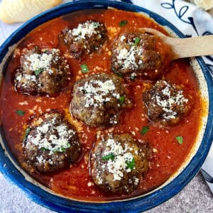 meatballs in sauce with parmesan on top in a blue bowl