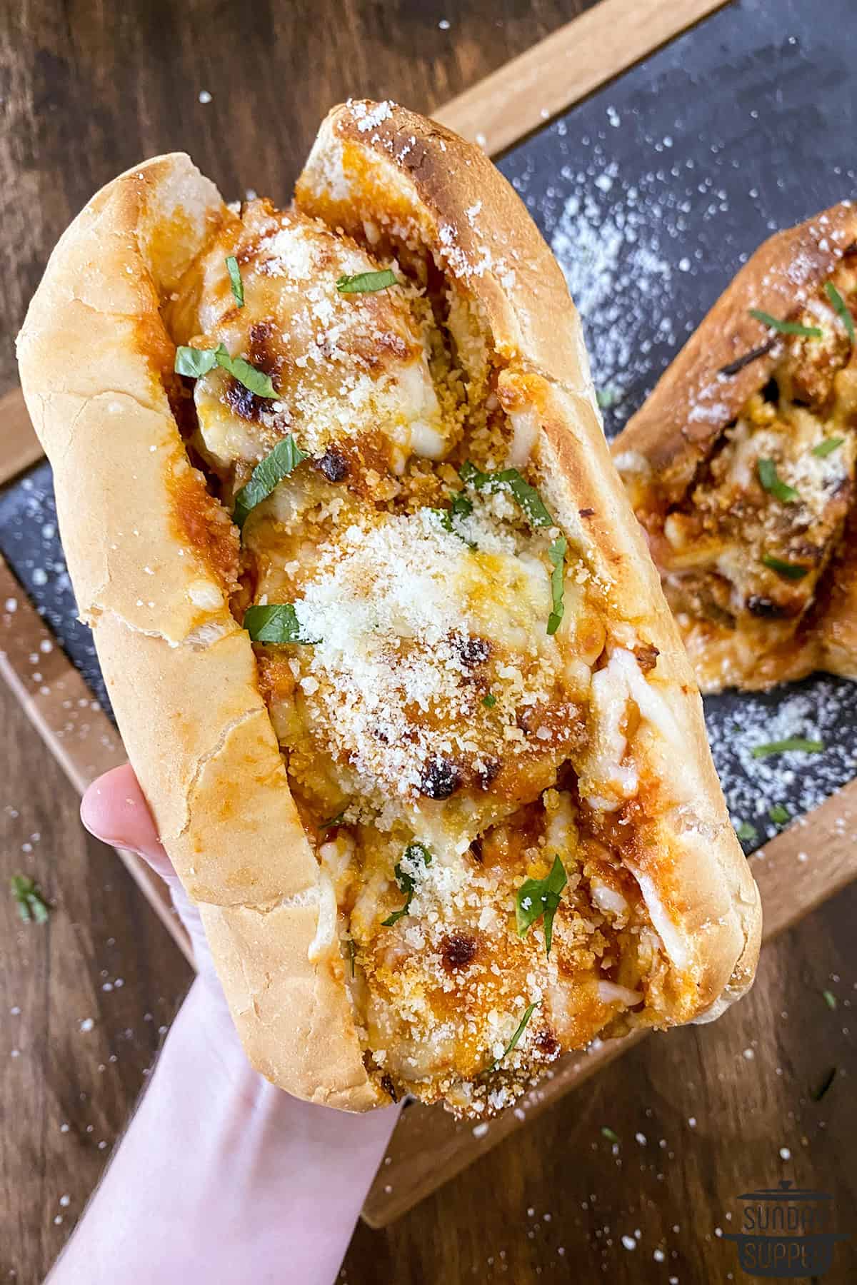 holding a meatball sub with parmesan