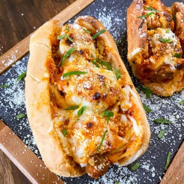 two meatball subs up close on a serving board