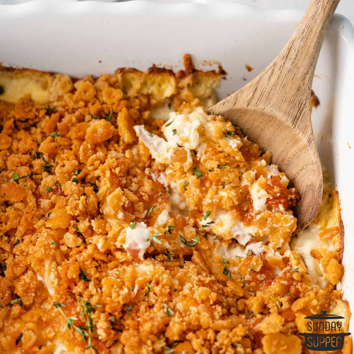 a wooden spoon scooping up creamy chicken casserole