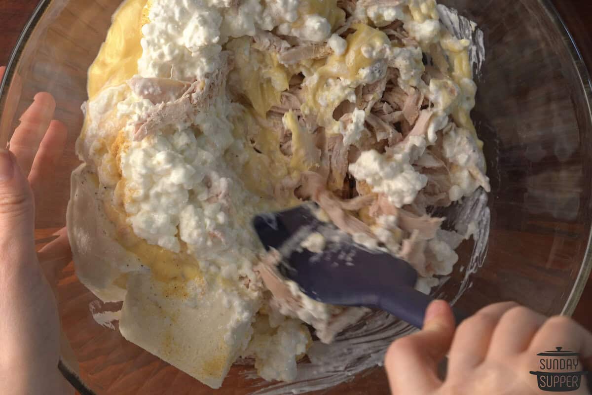 the casserole ingredients being mixed in a large bowl