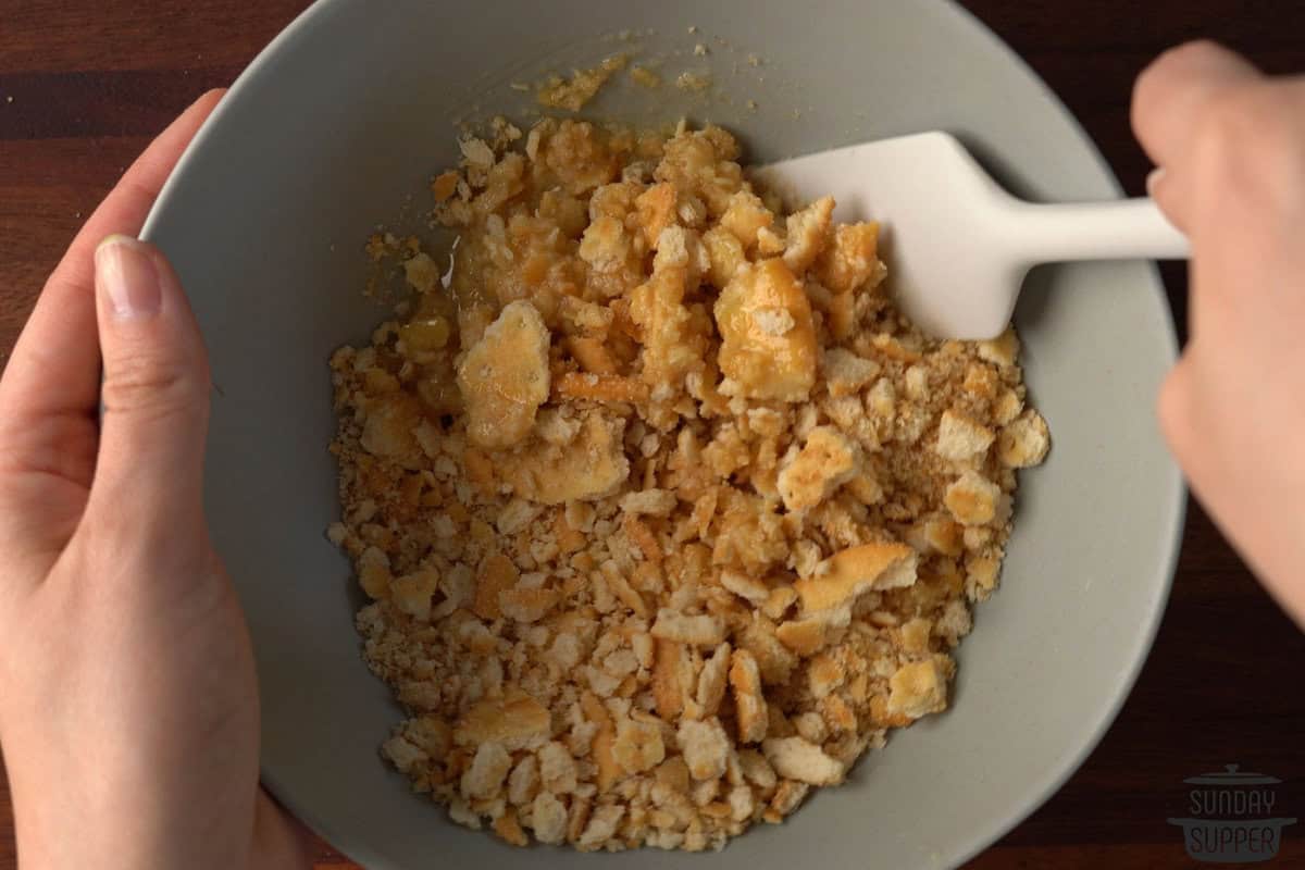 crushed crackers and butter being mixed in a small bowl