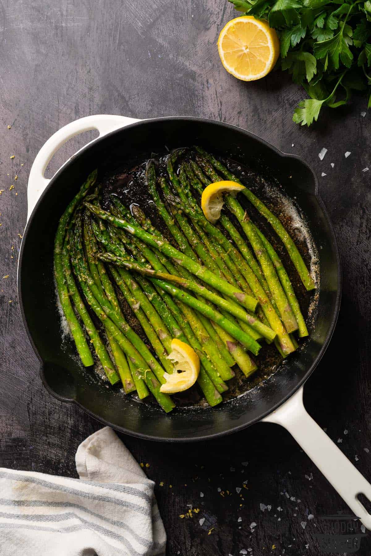 sauteed asparagus in a cast iron pan with lemon and parsley