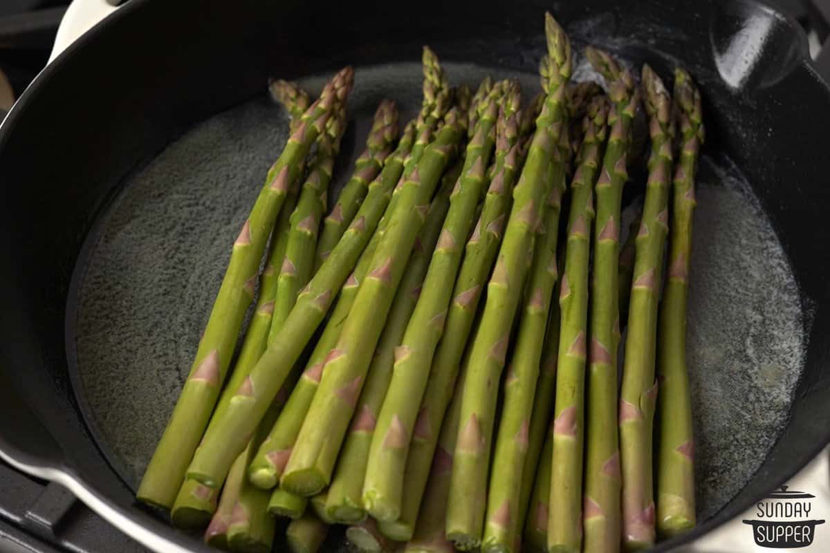 melted butter in a pan with the trimmed asparagus added