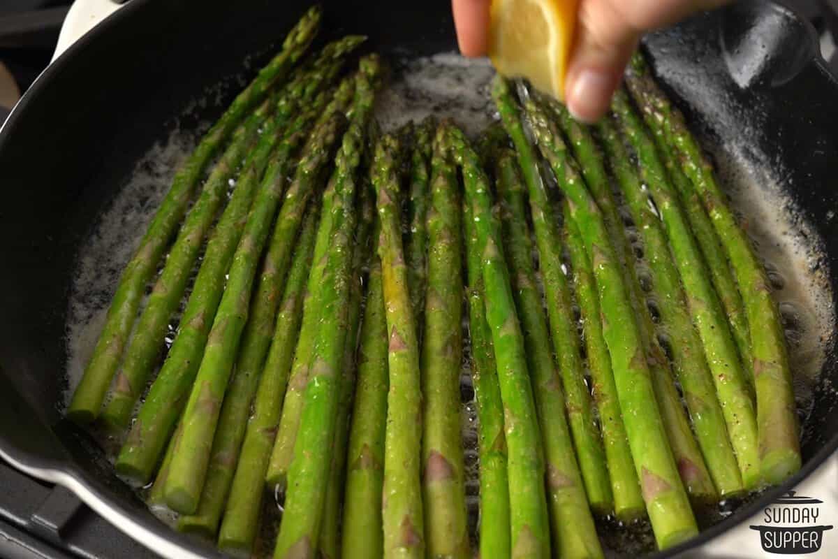 lemon juice being squeezed over the sauteed asparagus