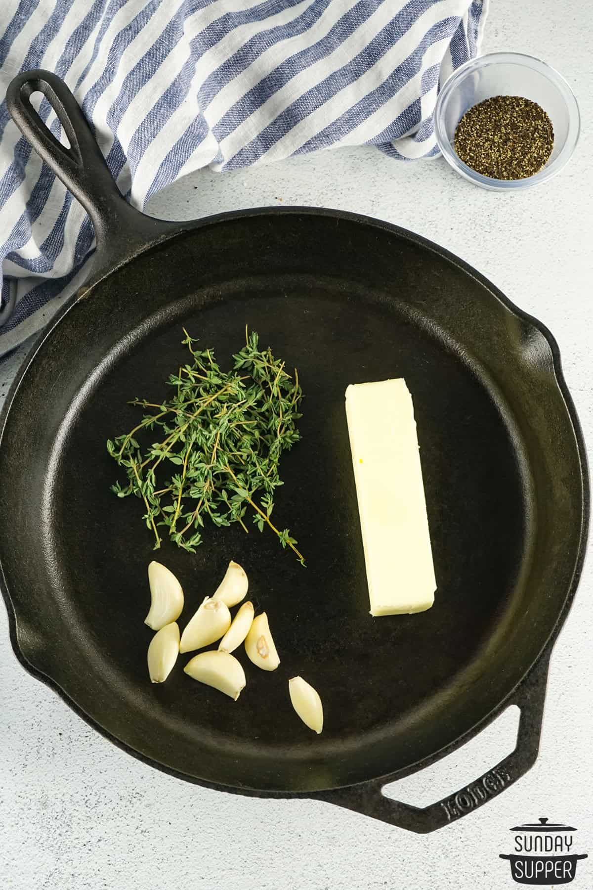 garlic cloves, butter, and fresh herbs in a skillet