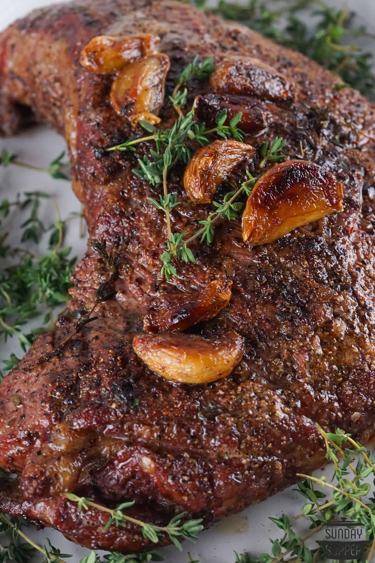 garlic cloves roasted on top of a tri tip