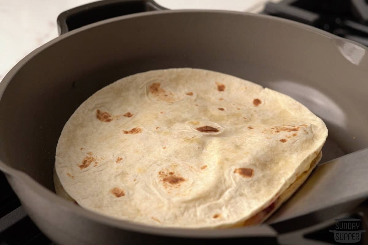 a turkey quesadilla in the pan being flipped with a spatula