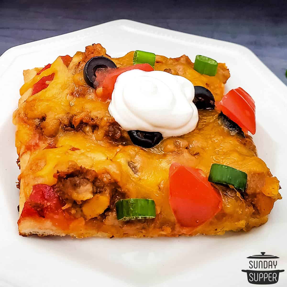 a slice of taco pizza with sour cream