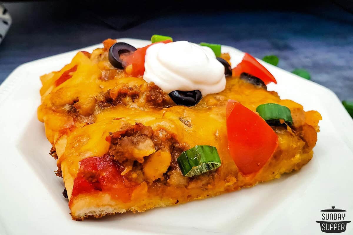 a slice of taco pizza on a plate ready to serve