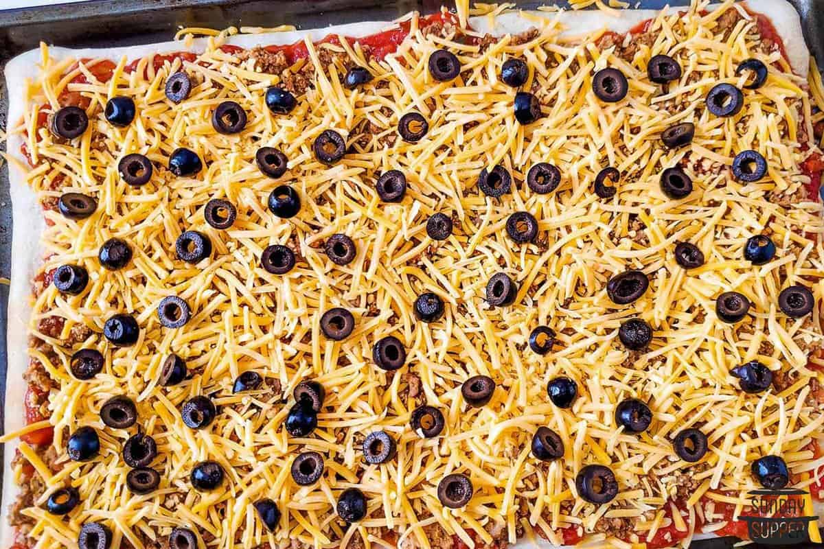 cheese and olives added to the pizza