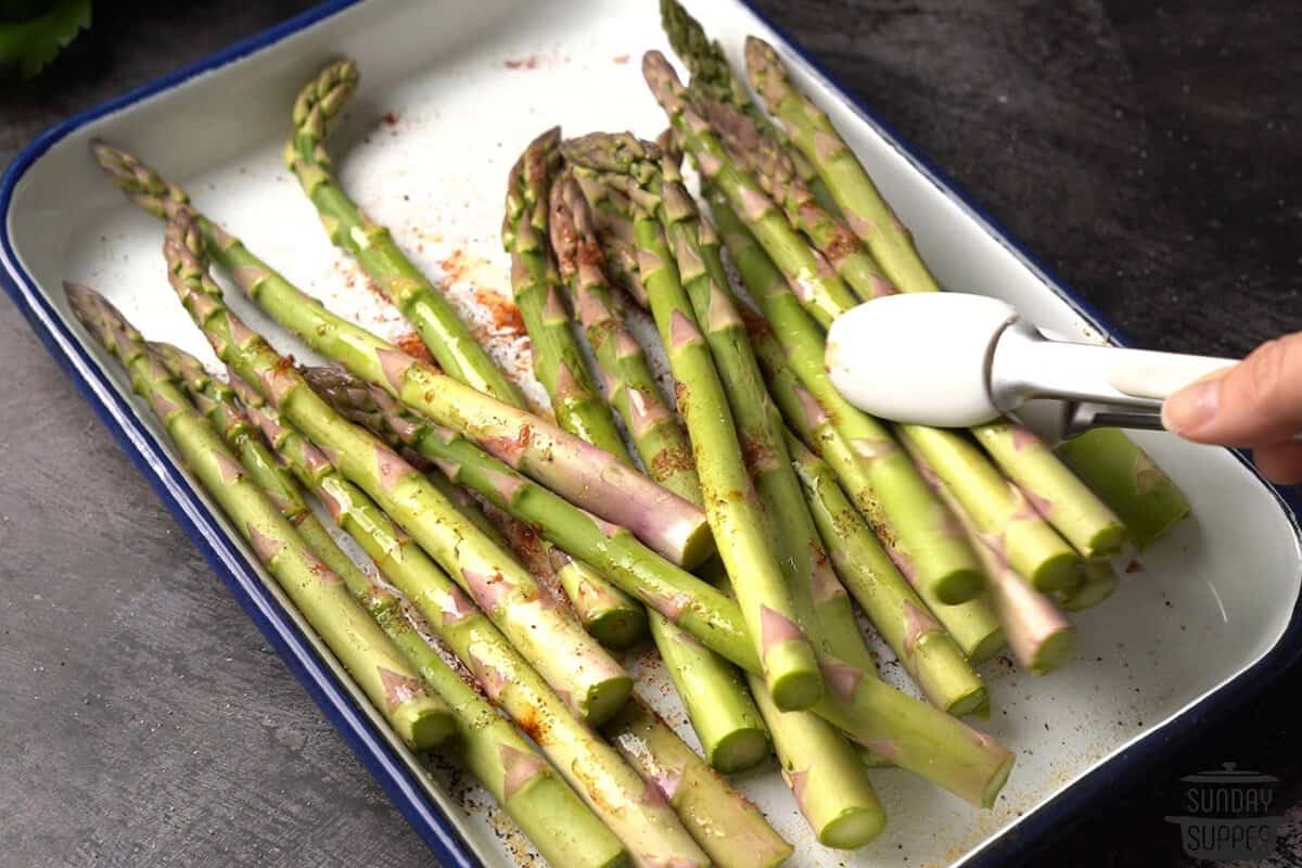 tossing asparagus with oil and seasonings using tongs