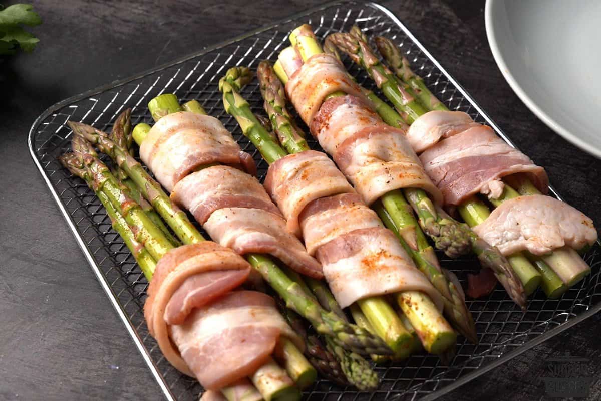 asparagus wrapped in bacon on air fryer tray