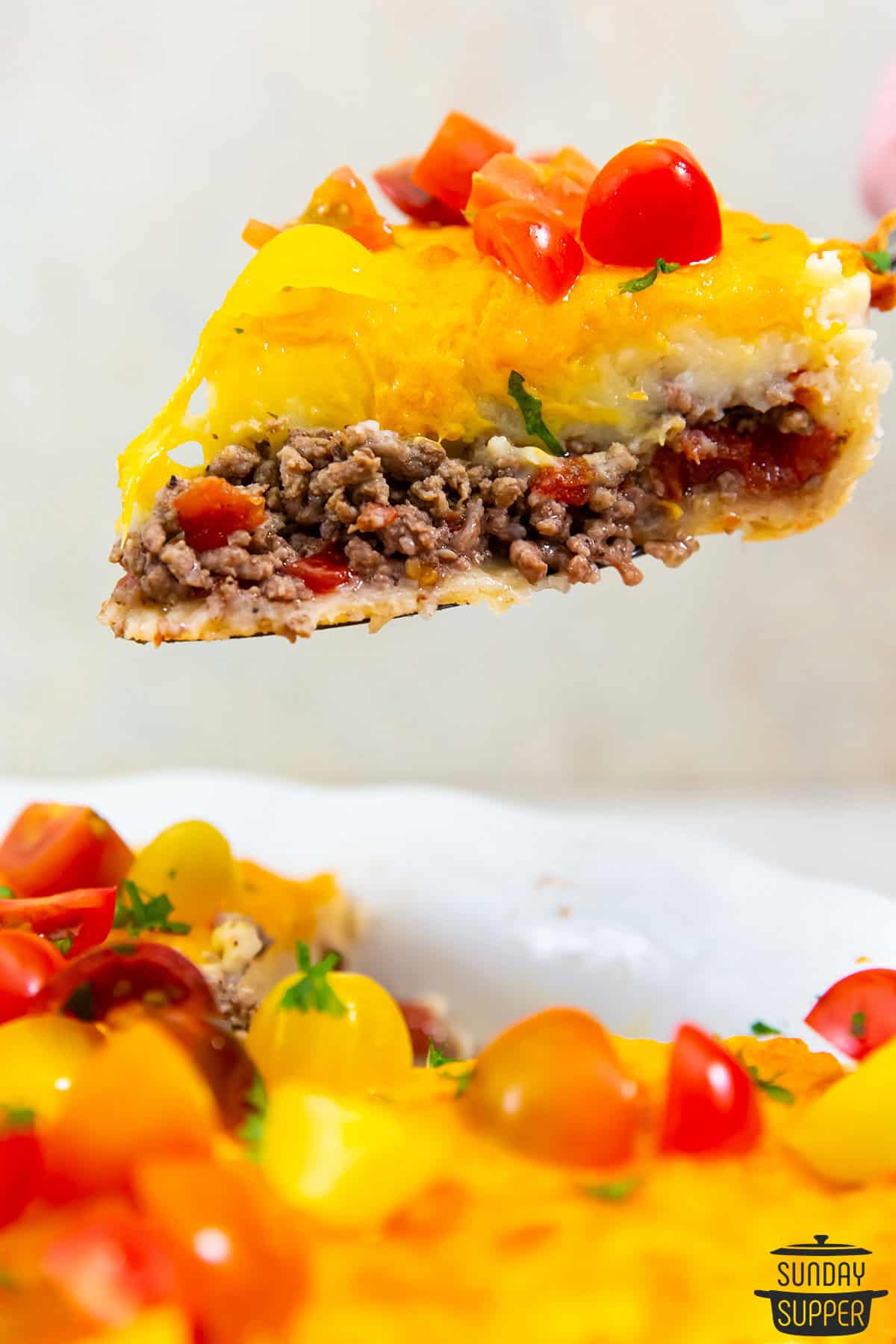 a slice of cheeseburger pie over a pie tin