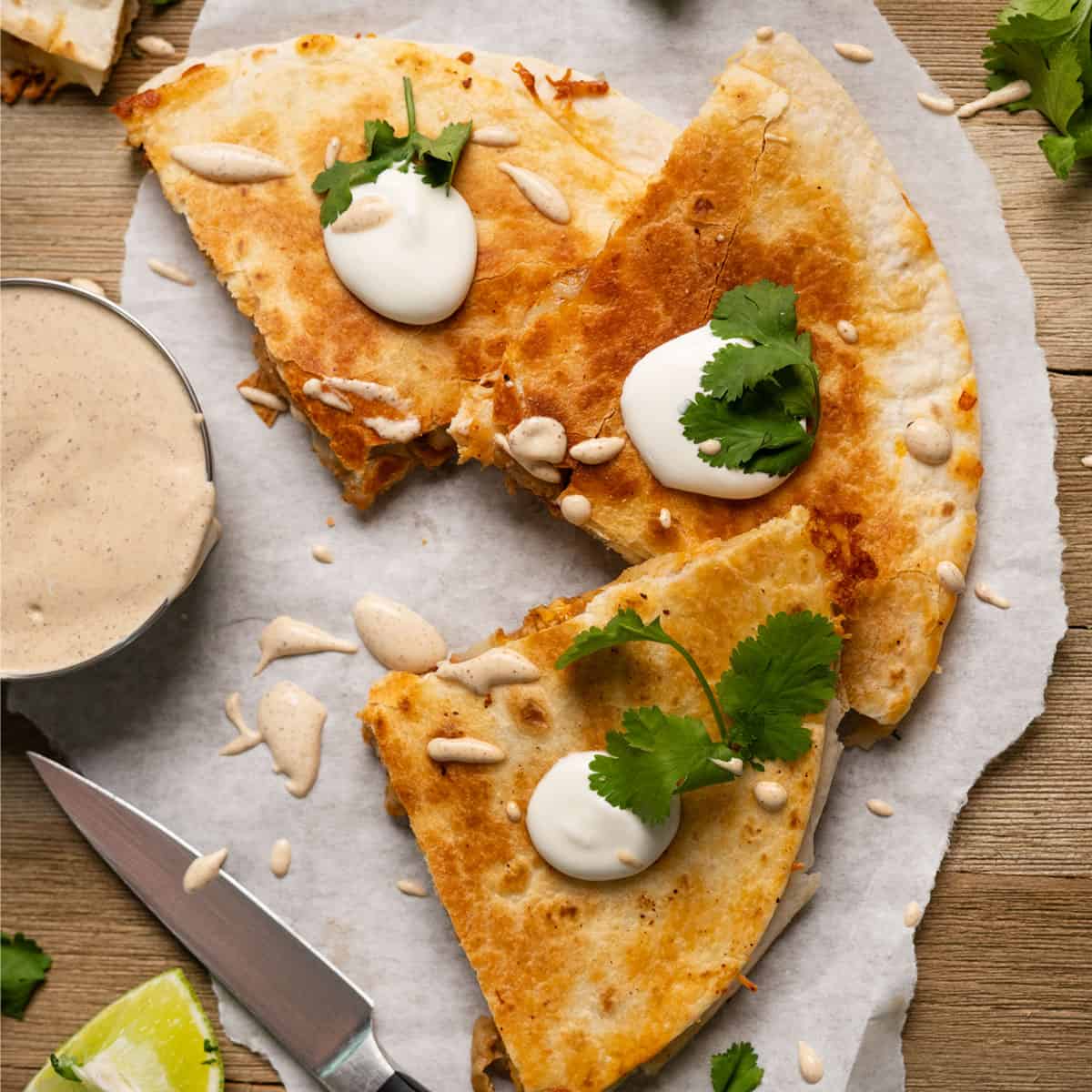 three slices of chicken quesadilla with sauce and cilantro