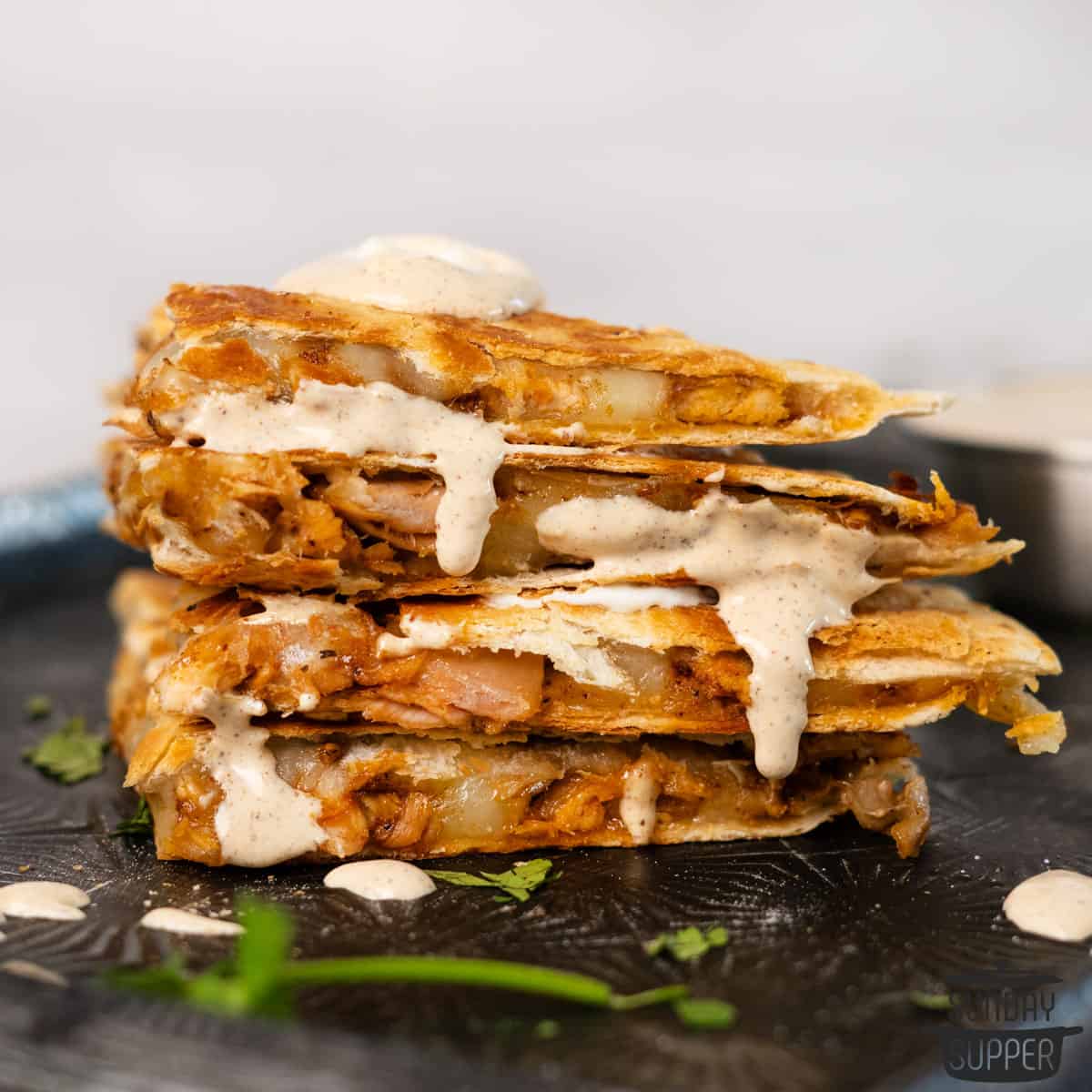 a stack of sliced chicken quesadillas with dipping sauce