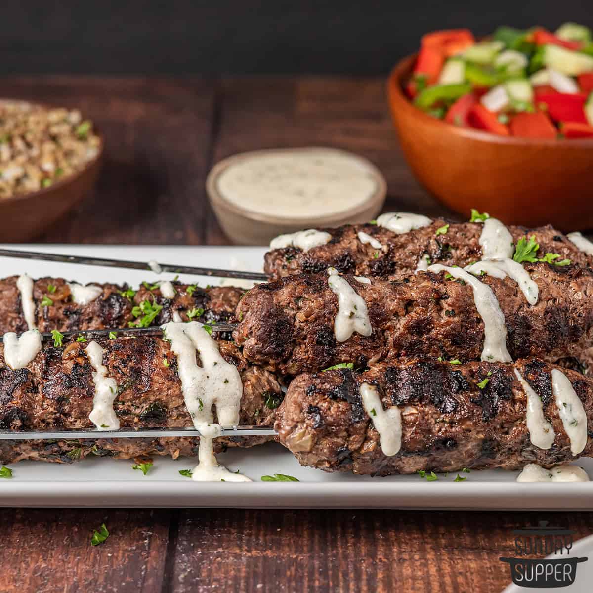 beef kebabs on a plate with garlic sauce