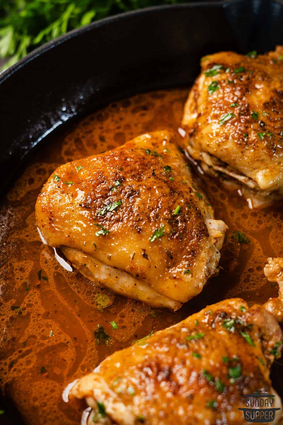 three cooked chicken thighs in pan sauce