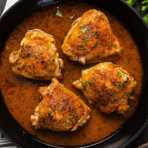 four chicken thighs fried in a pan