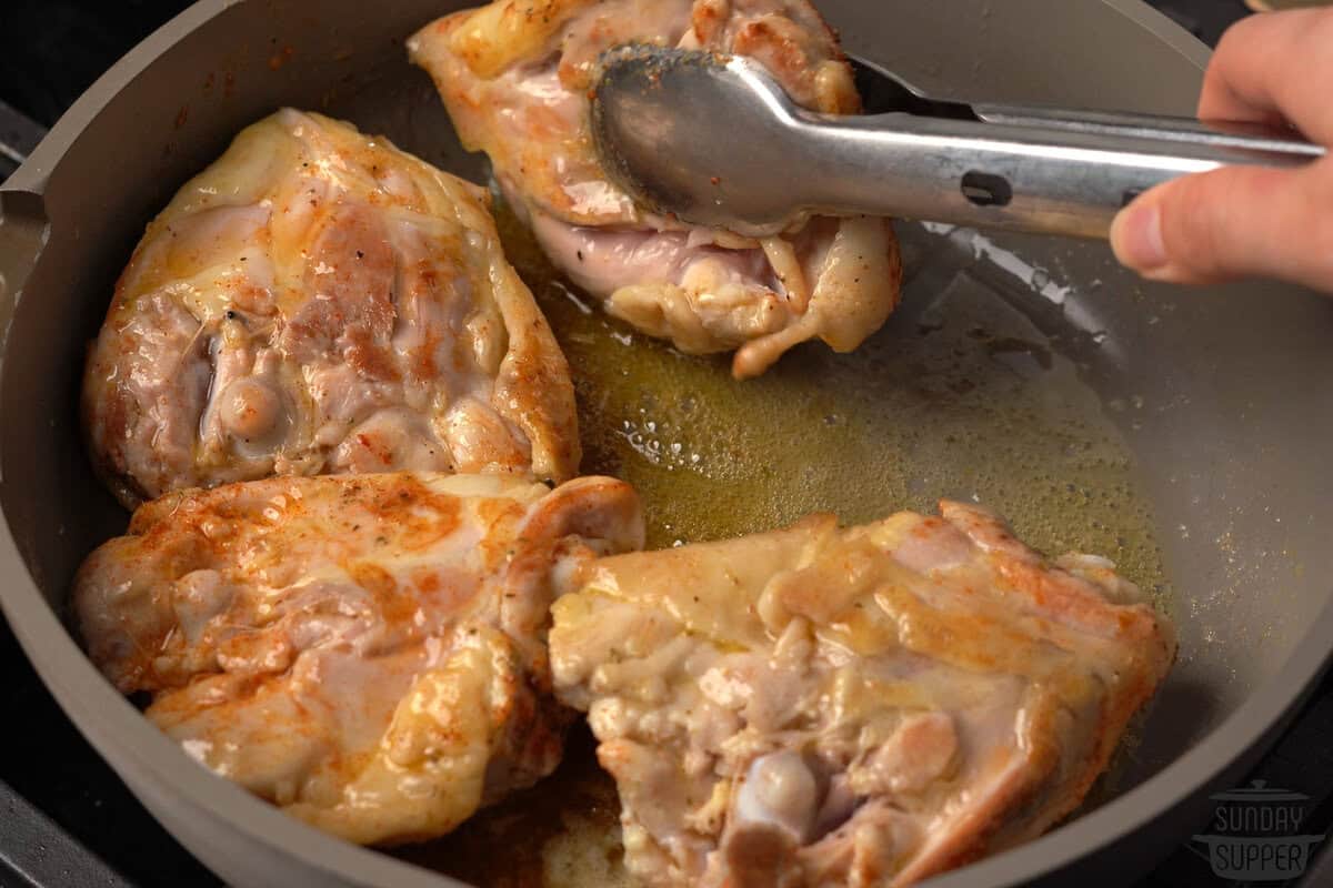 flipping the cooking chicken thighs