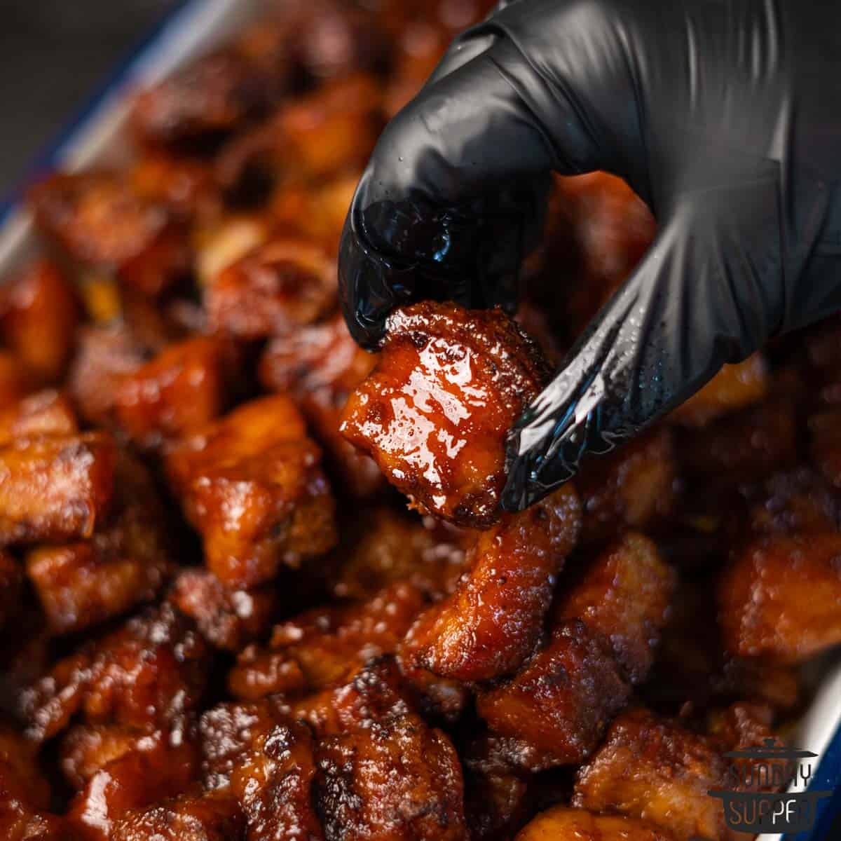 holding a burnt end pork belly piece