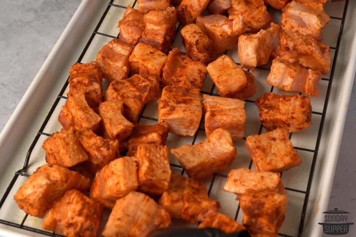 seasoned pork belly on a baking sheet with rack