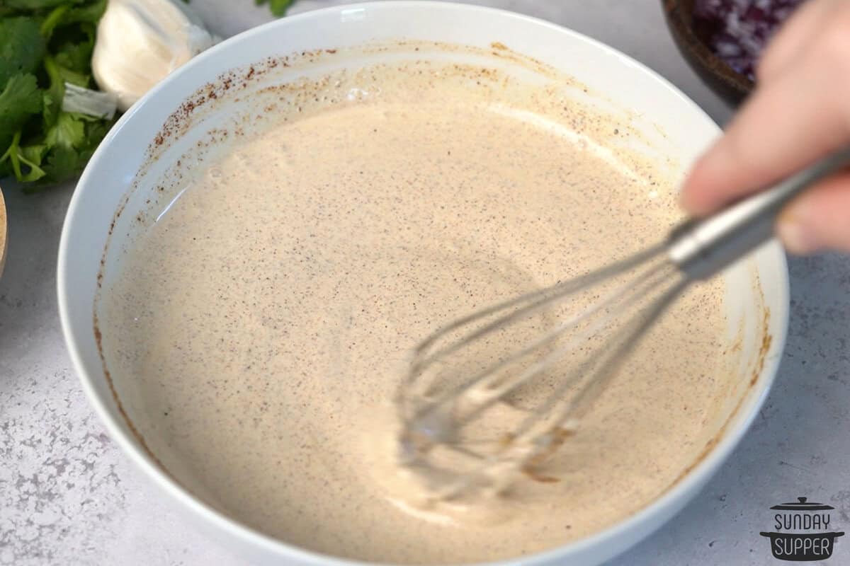 stirring quesadilla sauce in a white bowl