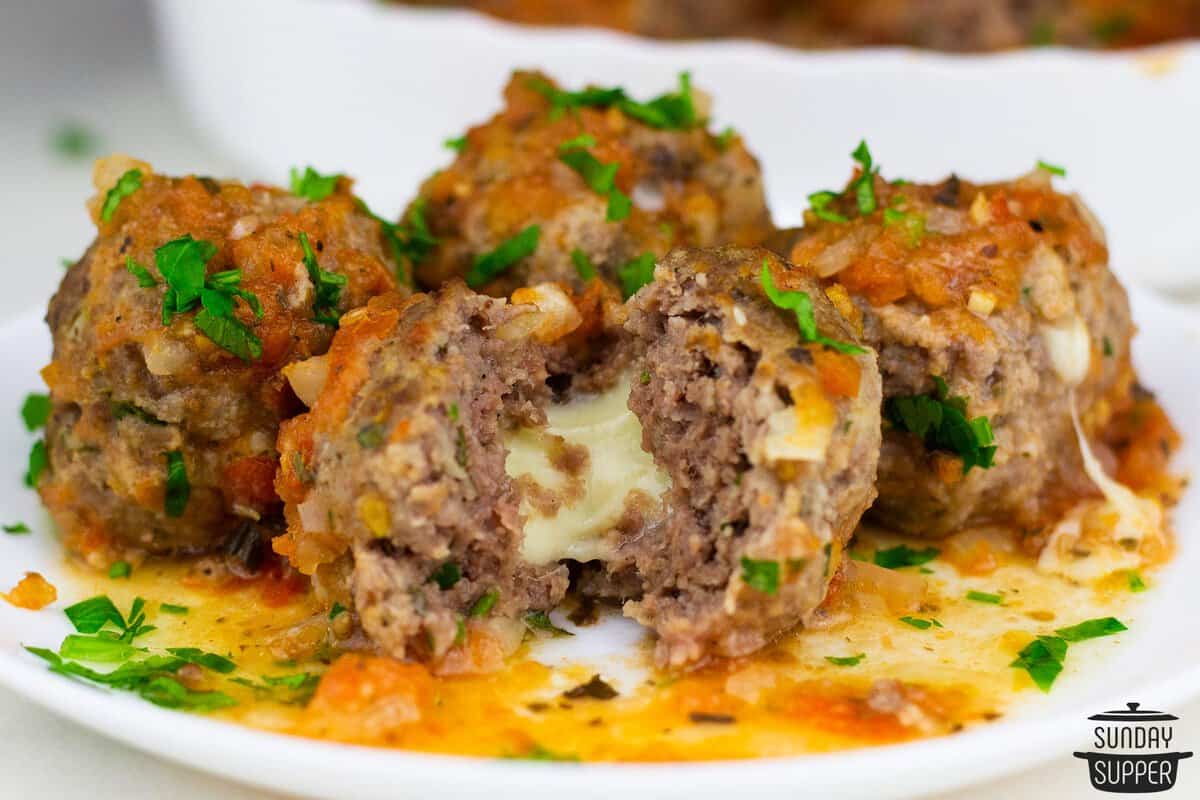 stuffed meatballs on a plate split to show the melted cheese