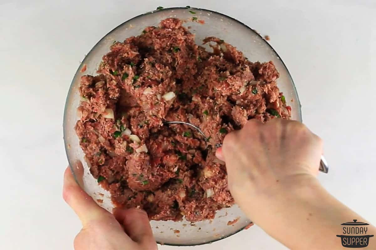 the meatball mixture being mixed in a bowl