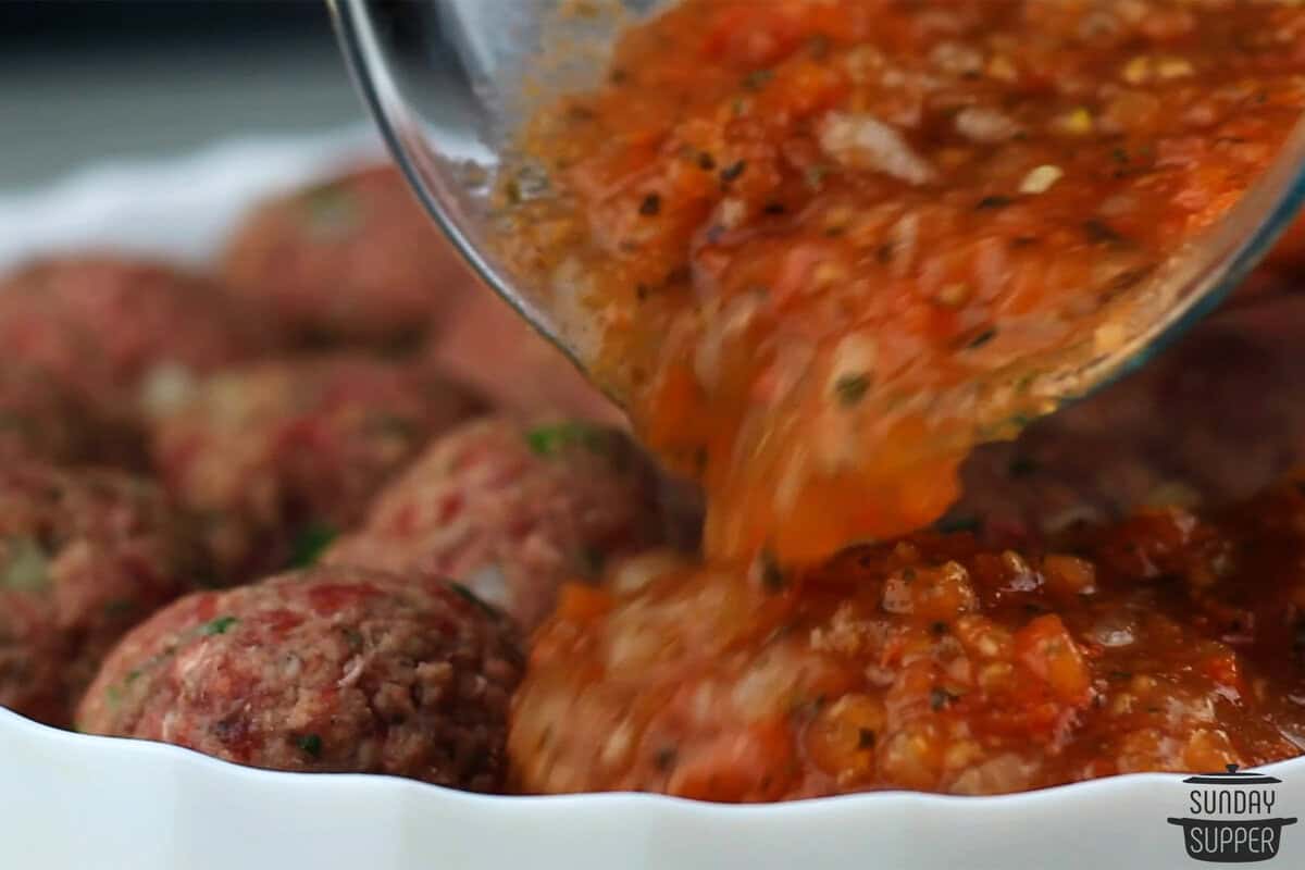 the sauce being poured over meatballs