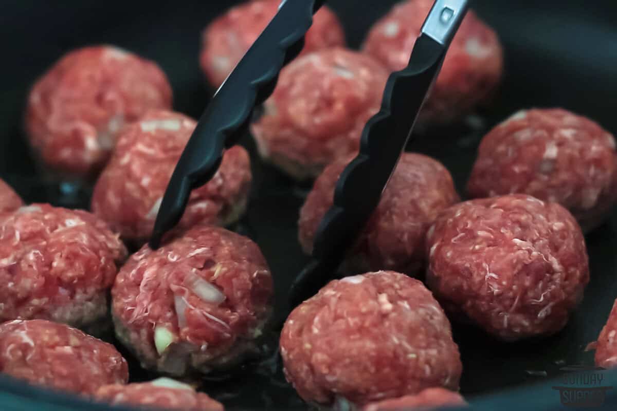 the meatballs being cooked in a skillet