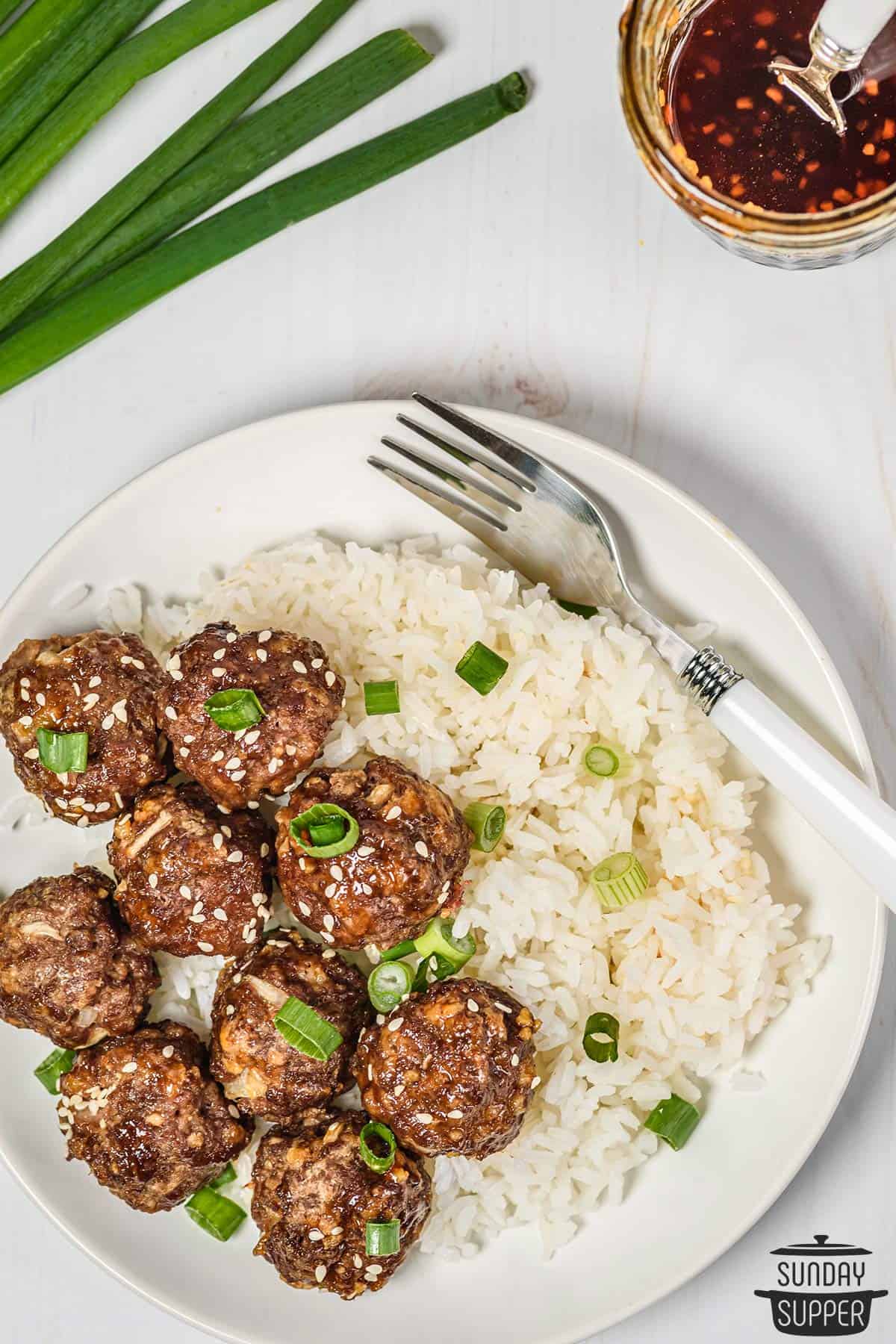 a plate of honey sriracha meatballs on a plate with rice