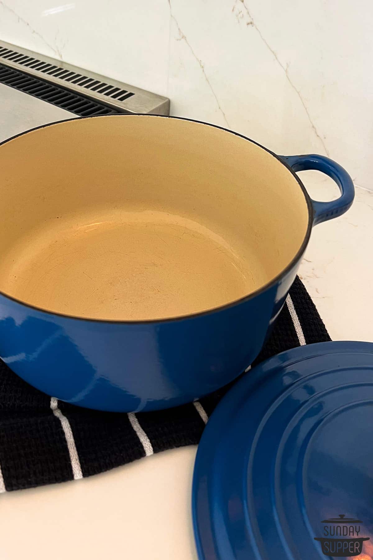 a blue dutch oven on the counter with the lid removed