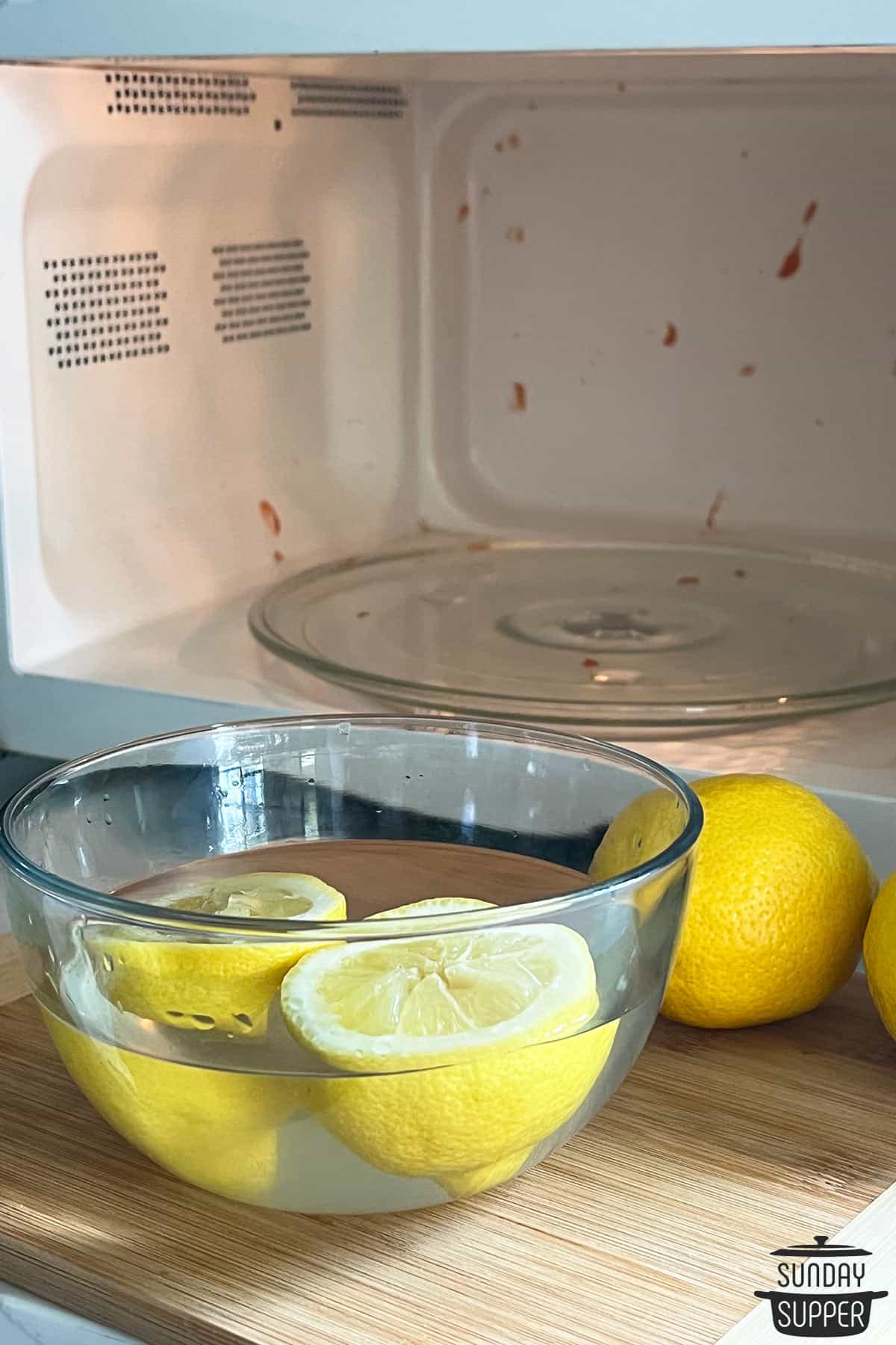 a lemon in a bowl of water in front of a dirty microwave