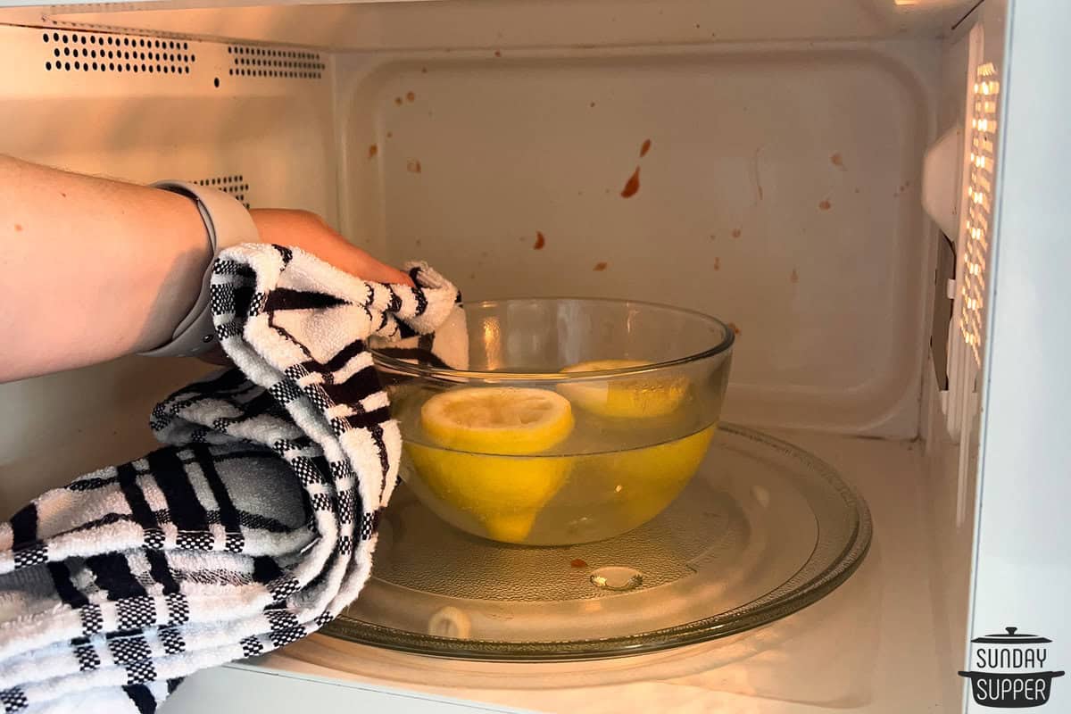 removing the bowl of lemons and water using a kitchen towel