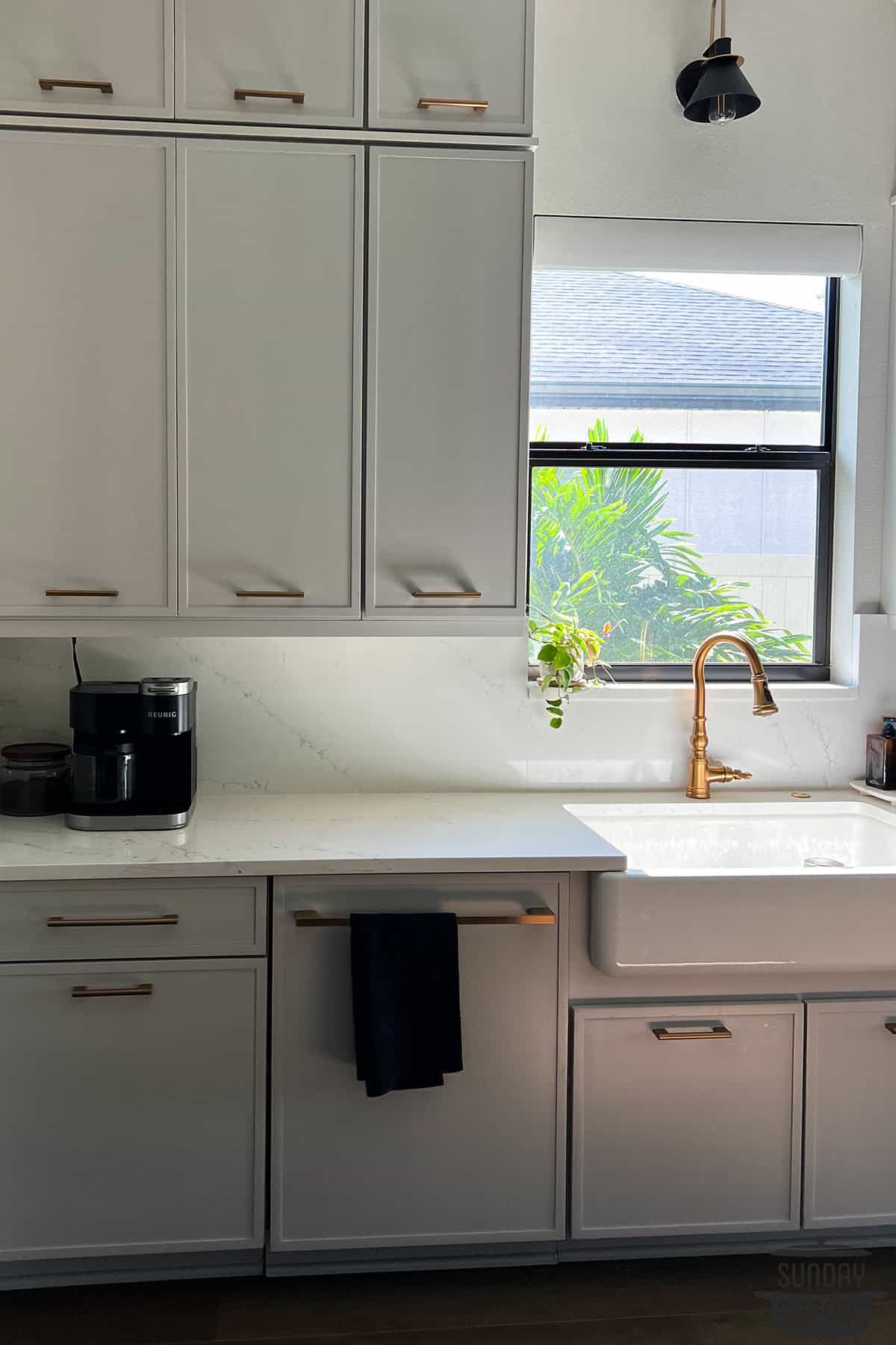 a clean quartz countertop with a sink and window