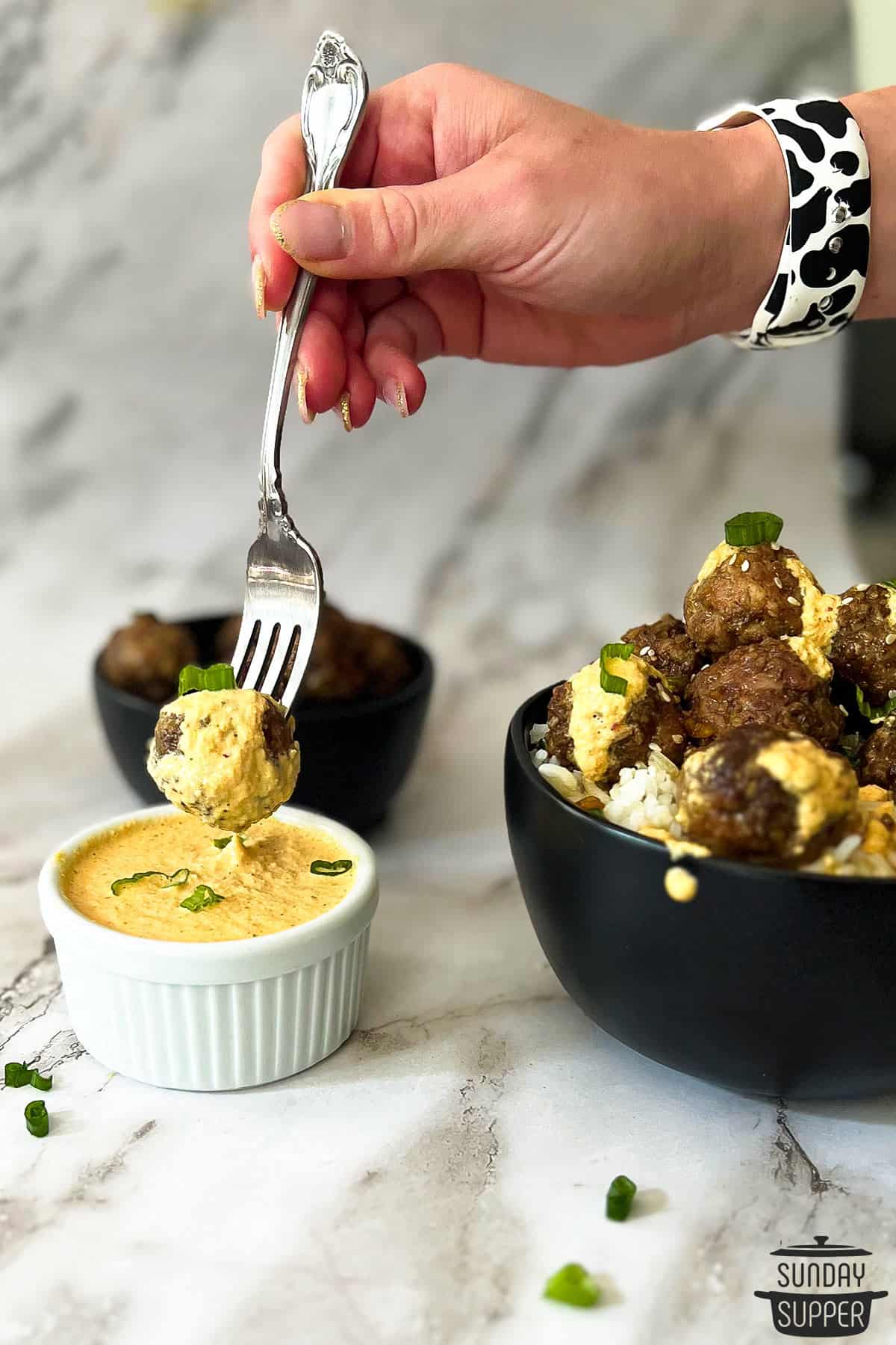 a korean meatball being dipped in kimchi mayo