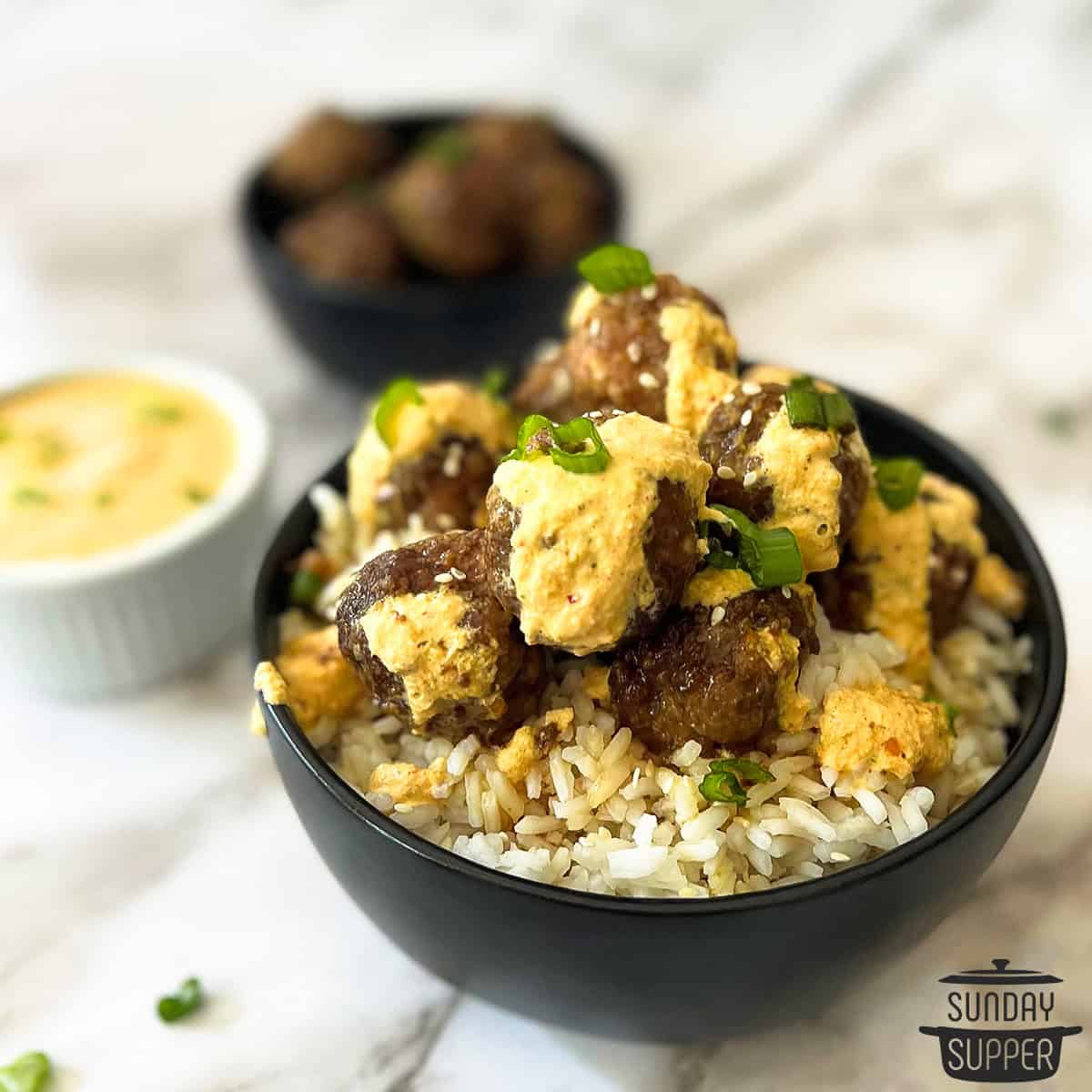 a bowl of white rice with korean meatballs and sauce