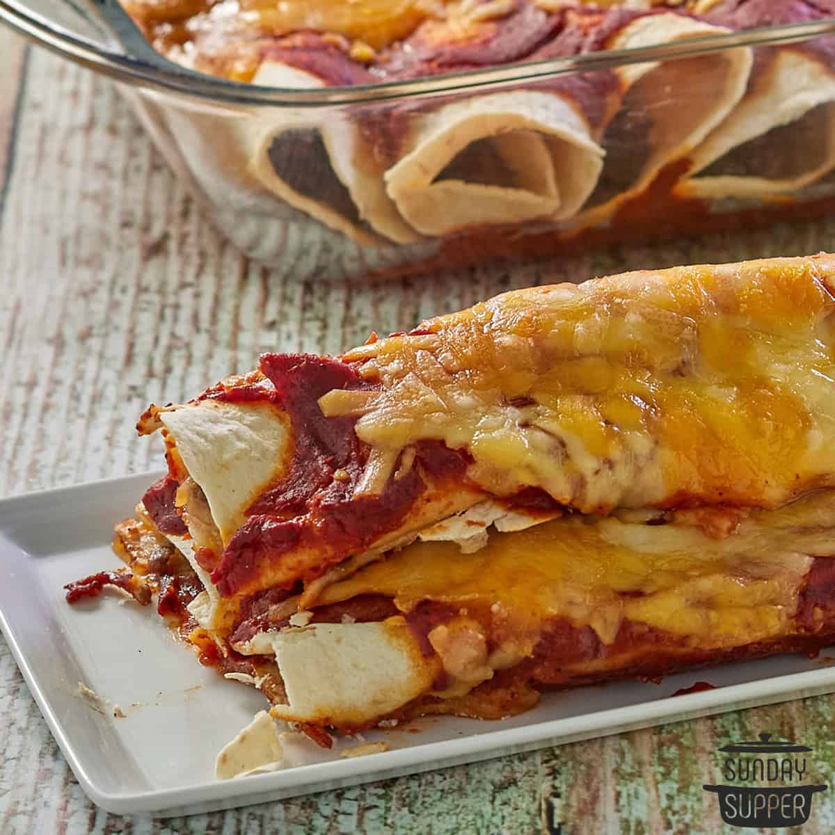 three beef enchiladas on a plate with cheese and sauce