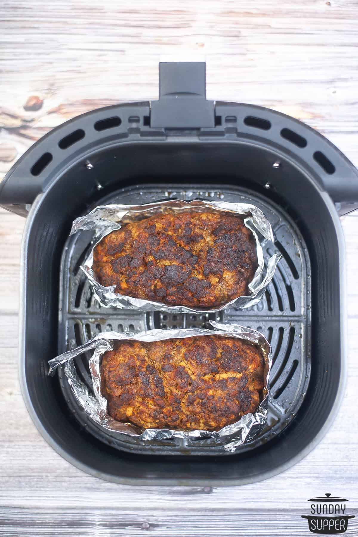 two cooked meatloaves in an air fryer